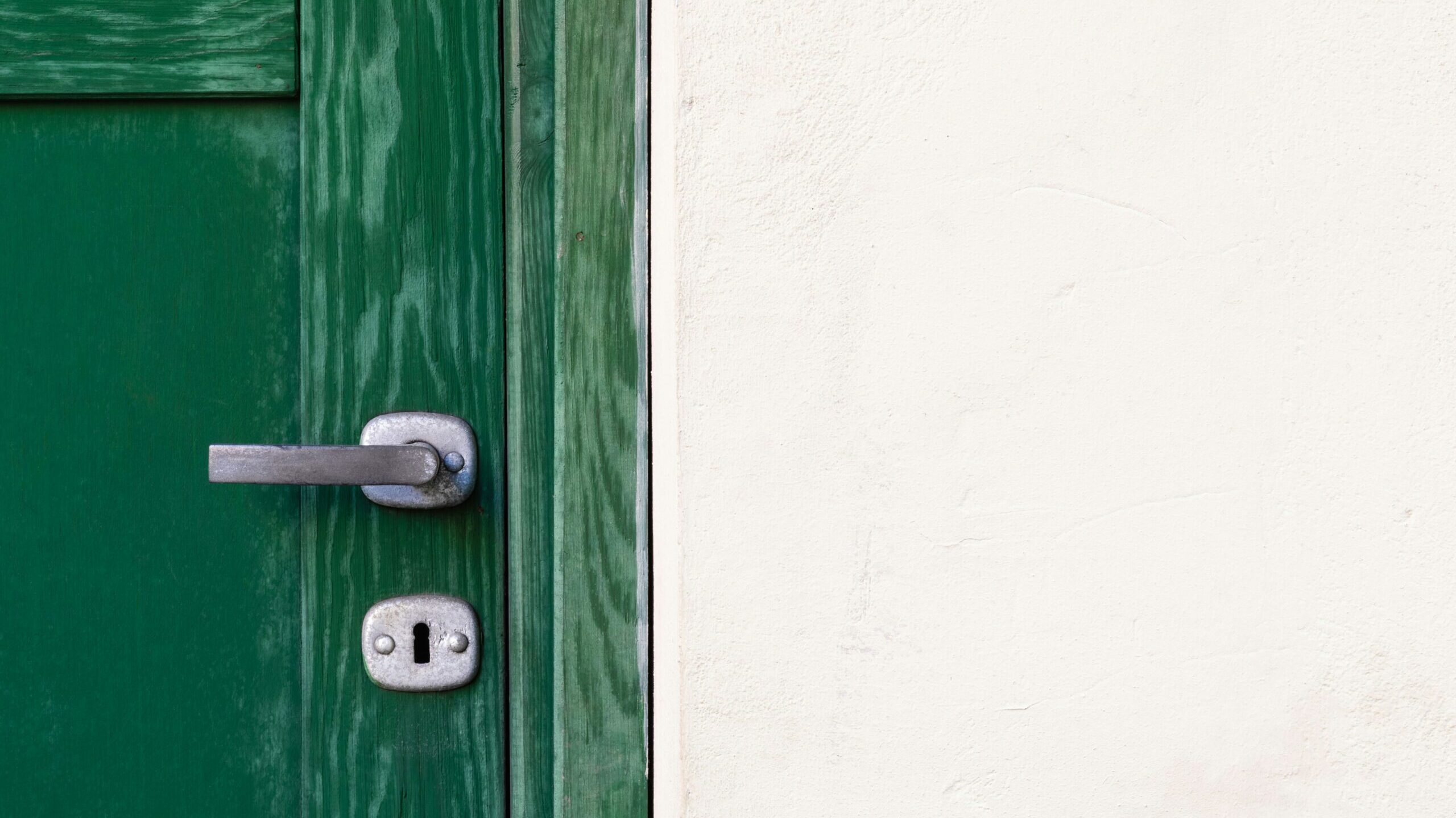 green wooden door beside white wall